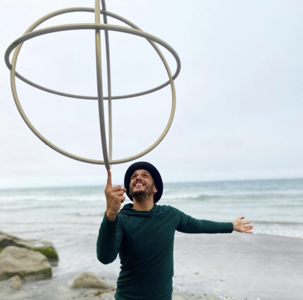 man on beach balancing large circiles