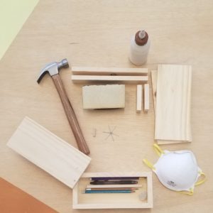 close up of flat lay tools and supplies in craft kit including hammer, glue, wood, box