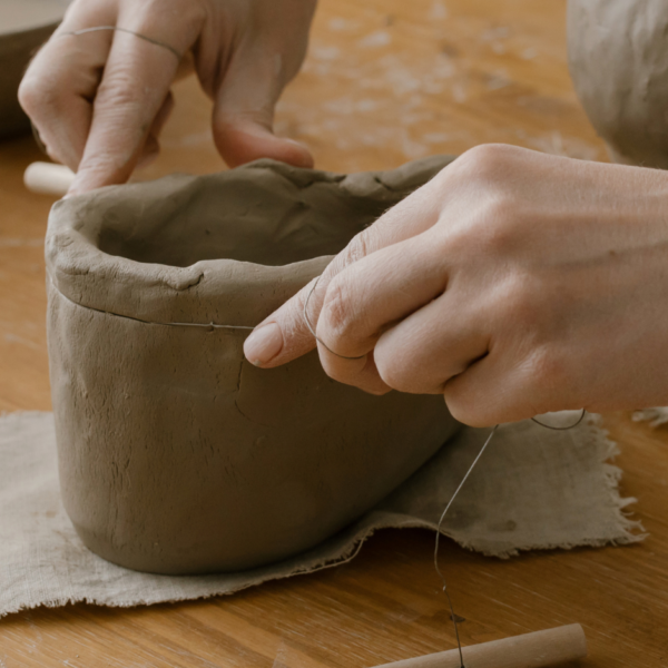 hands creating a clay vessel