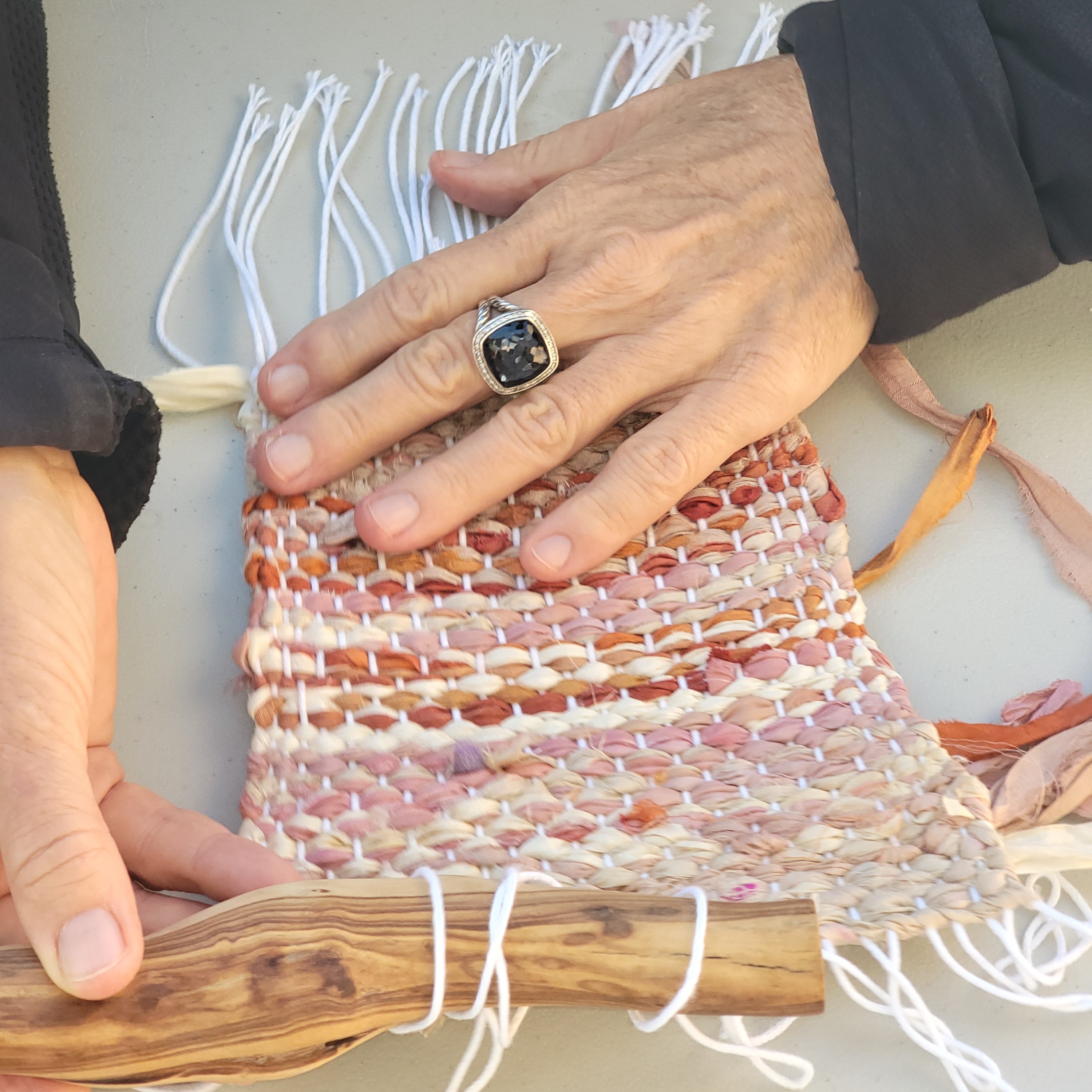 hands with a handwoven silk wall hanging and rod