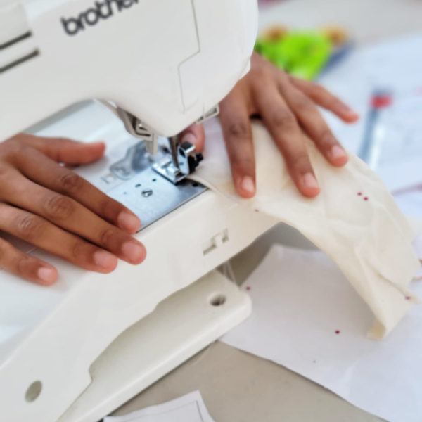 hands sewing fabric with use of a white sewing machine