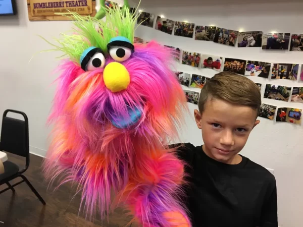 child displaying handmade muppet-like puppet