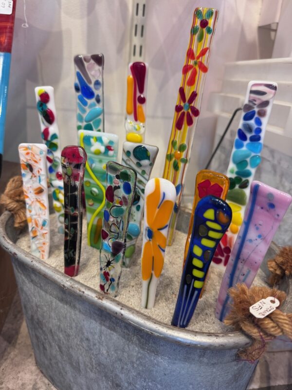 fused glass garden stakes in a bucket of sand