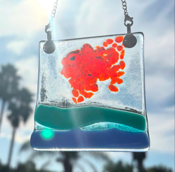 fused glass light catcher with fish and water shining in sunlight