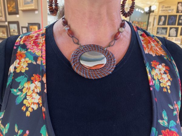 person wearing a pine needle basket woven necklace with large stone cabochon