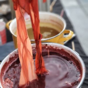 two dye pots with hand lifting madder root red dyed silk fabric from one dyepot