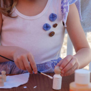 girl painting wooden peg doll