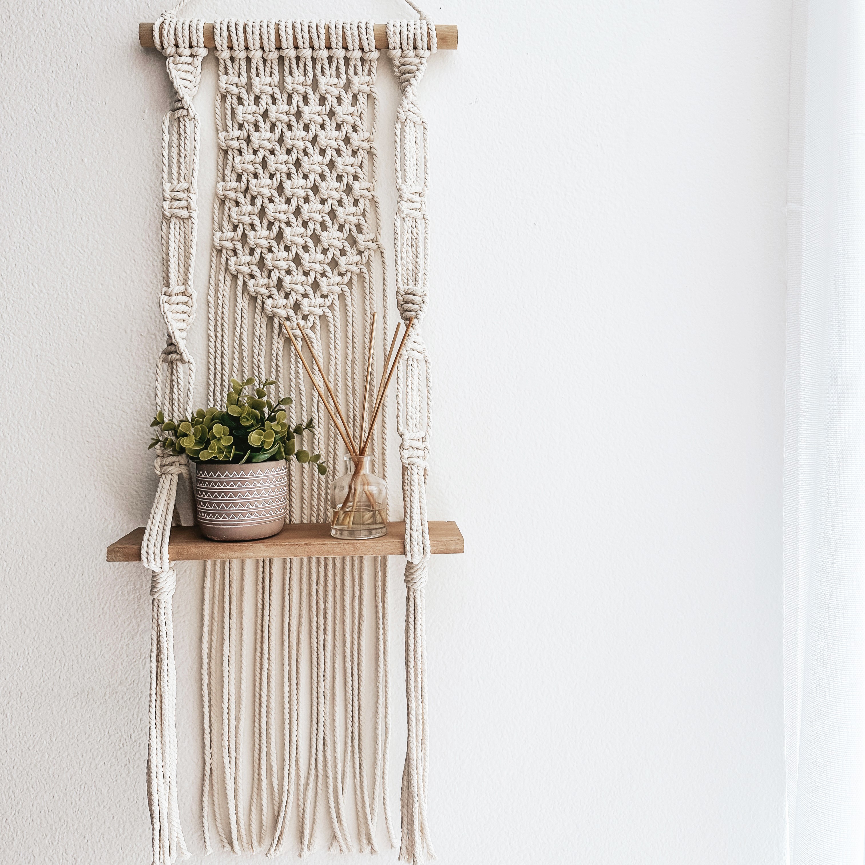 wall hanging macrame shelf with potted plant