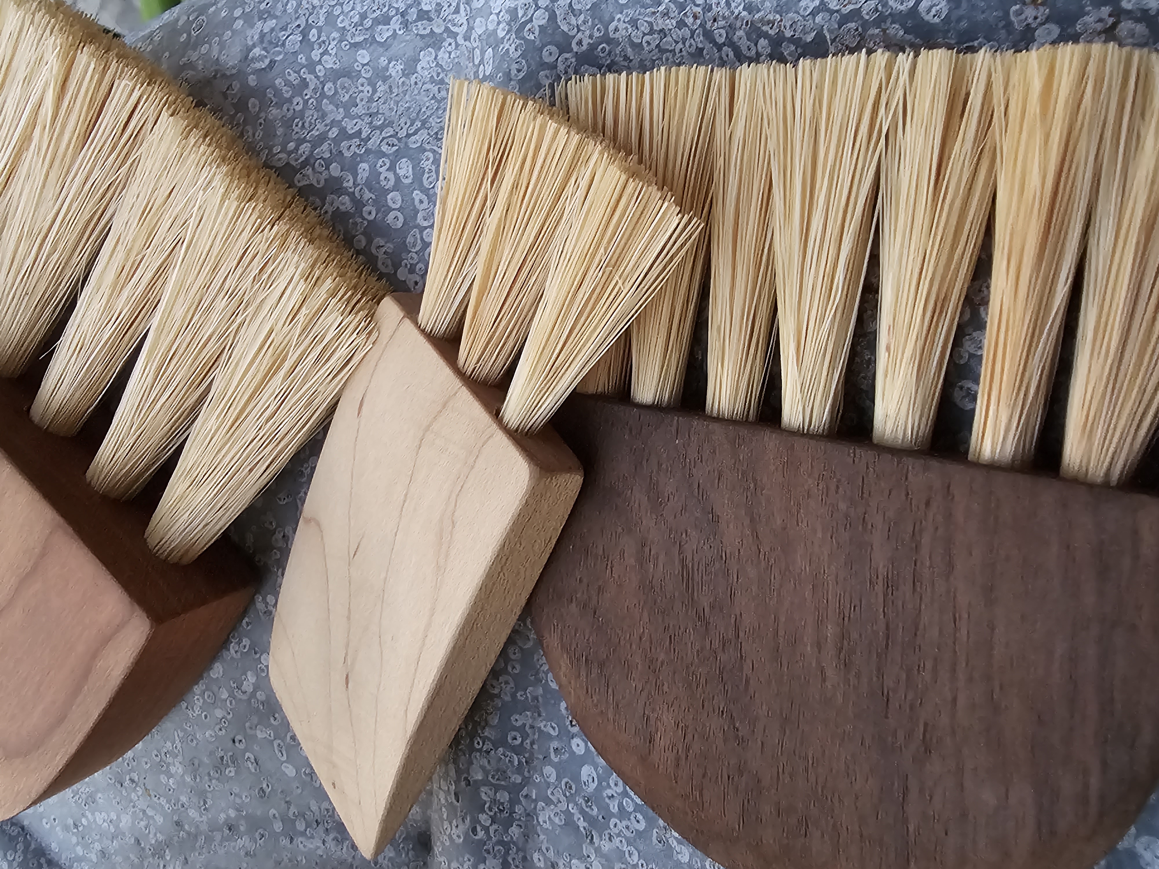 close up of handmade wooden handled small brushes on metal surface