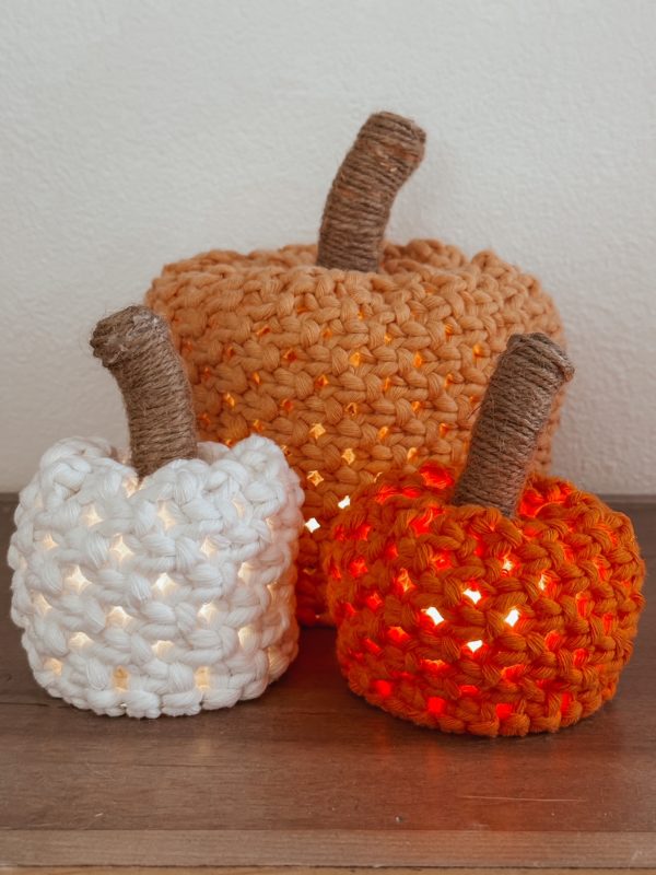 close up of three macrame decor pumpkins with lights shining from inside each