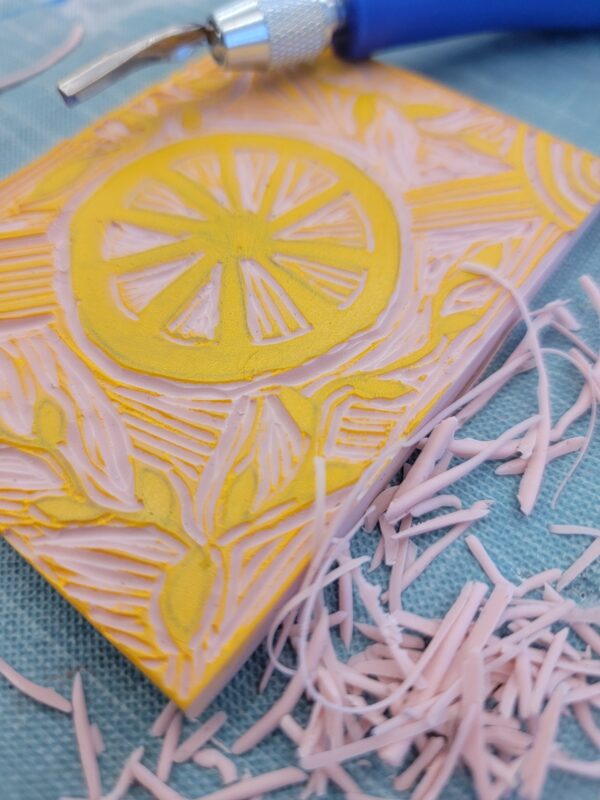 close-up of carving tool and linoleum block print with citrus pattern