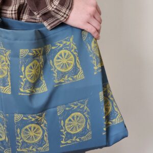 close up of block printed blue tote bag on woman's shoulder with white background