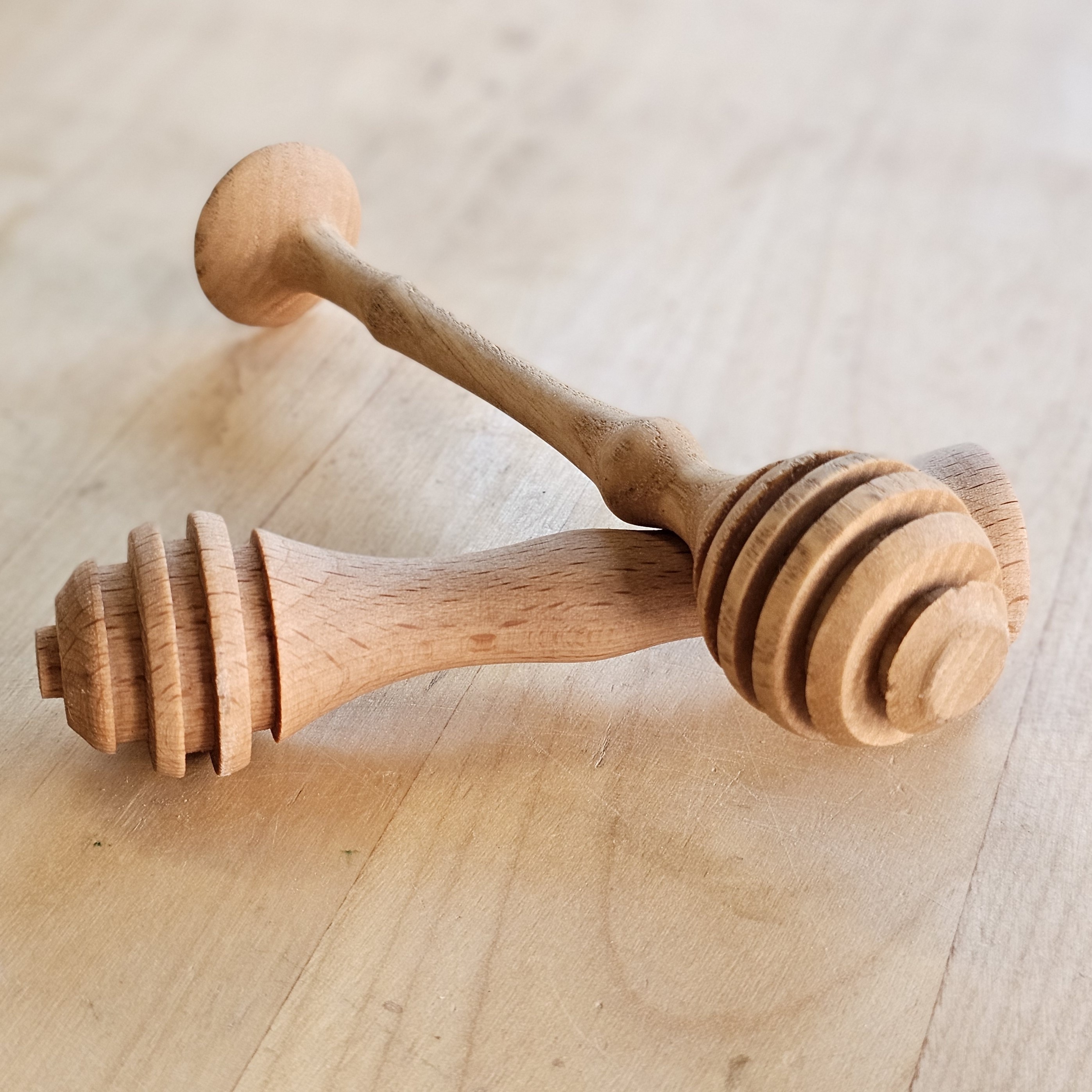 two honey dippers turned on a lathe resting on a table