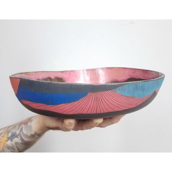 close up of hand holding surface design colorful clay bowl