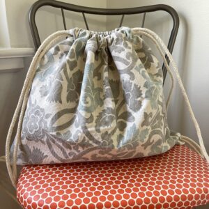 drawstring backpack resting on a spotted red chair
