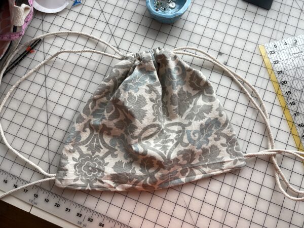 drawstring backpack laying on a fabric cutting grid
