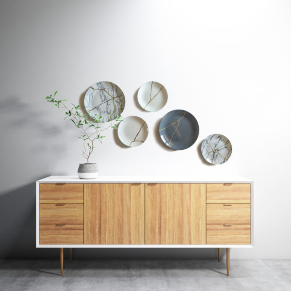 Kintsugi plates on grey white background wall hanging over a credenza
