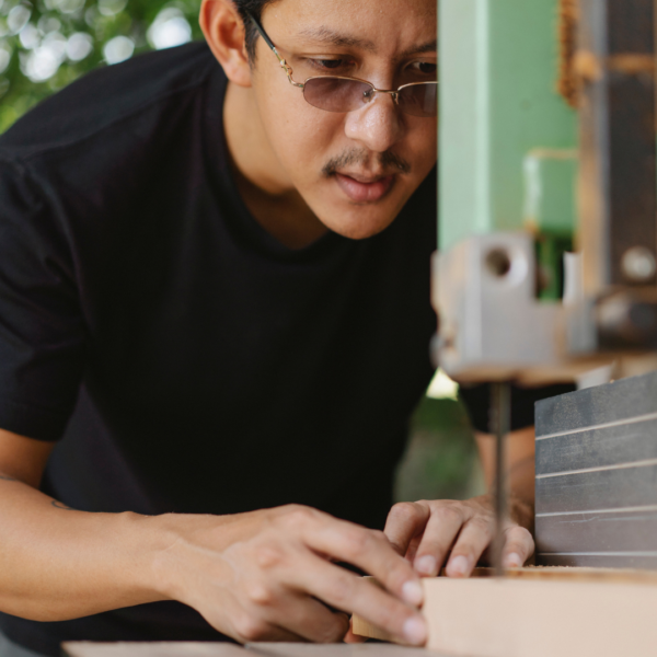 man using a bandsaw in a woodshop