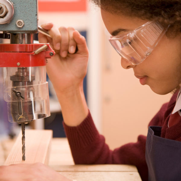 woman using a drill press in woodshop