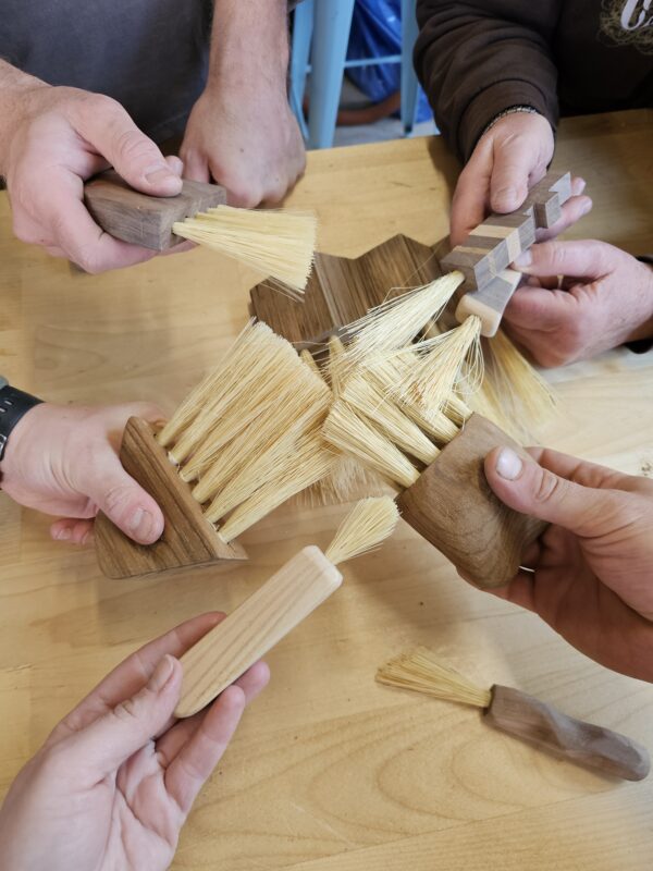 hands holding handmade wooden brushes
