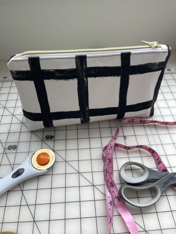 close up of a black and white fabric zipper pouch and scissors and measuring tape