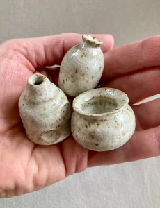 close up of tiny cream colored clay pots in hand