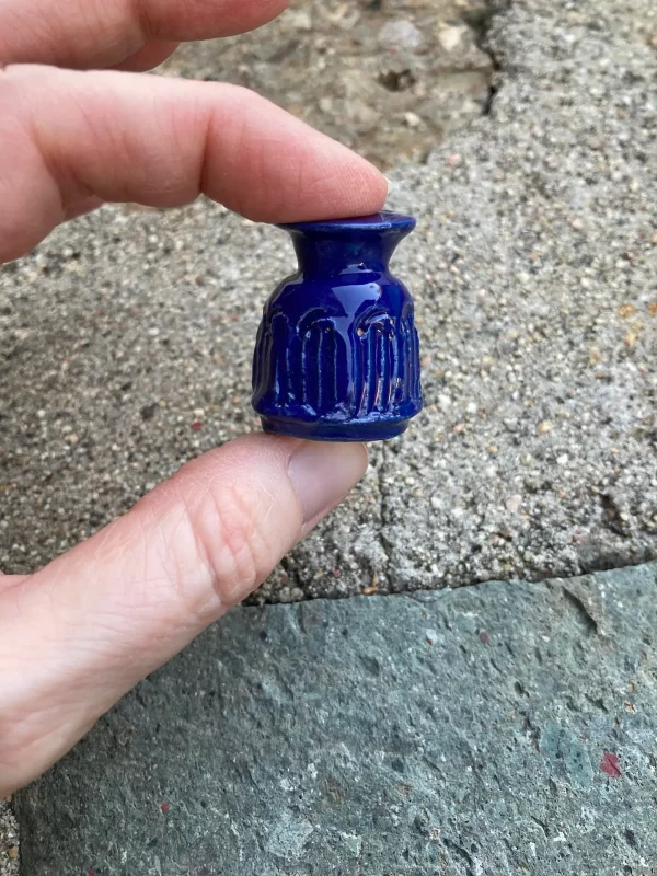 close up of tiny blue clay vase in hand