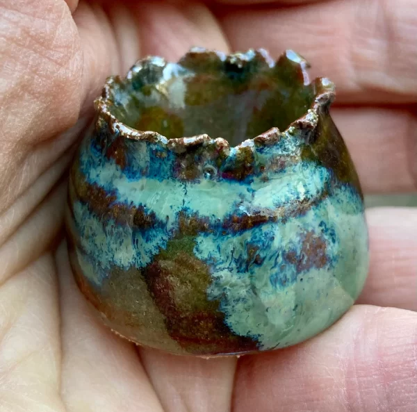 close up of tiny green speckled clay pot in hand