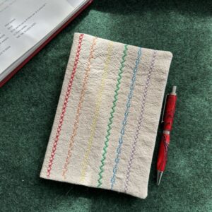 sample sewn square with different colored stitches on desk with pen