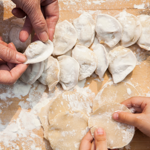 hands wrapping and pinching dumplings