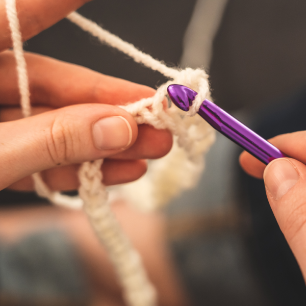 fingers holding yarn an crocheting with hook