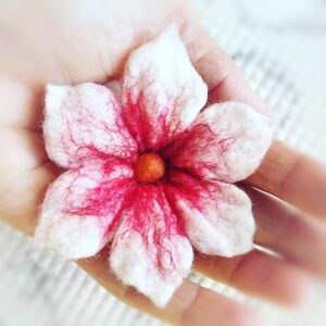 hand holding a pink and white wet felted flower