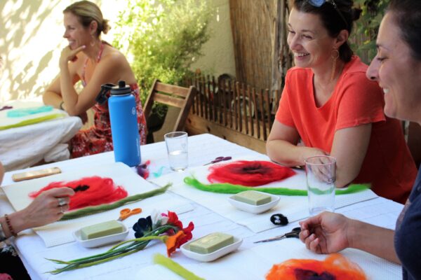 a group of people at a table learning to wet felt flowers