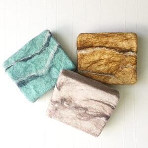 three bars of handmade wet felted soap in blue, pink and gold fibers