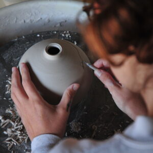 woman working on pottery at the ceramics wheel