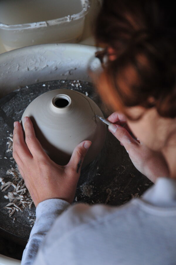 woman working on pottery at the ceramics wheel