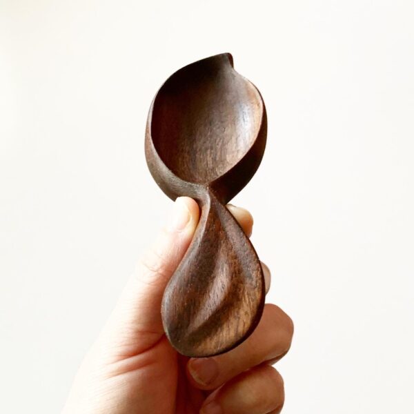 close up of hand holding a wooden power carved spoon