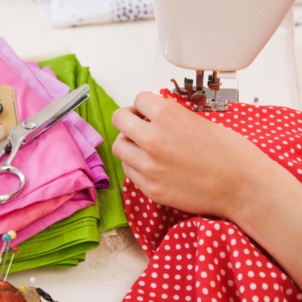 person sewing polka dot red fabric with sewing machine