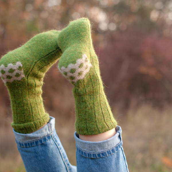 two feet with handknit green socks outdoors