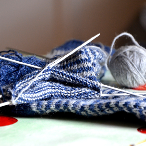 knitting needles and blue and grey yarn mid-project