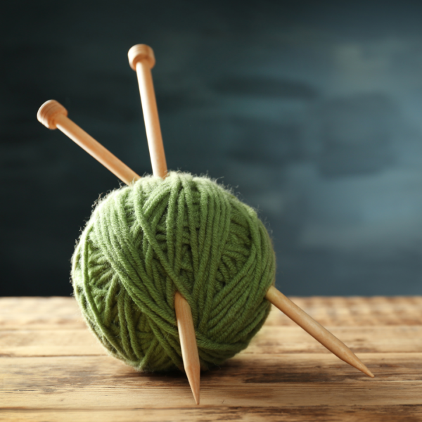 ball of yarn with knitting needles resting on table