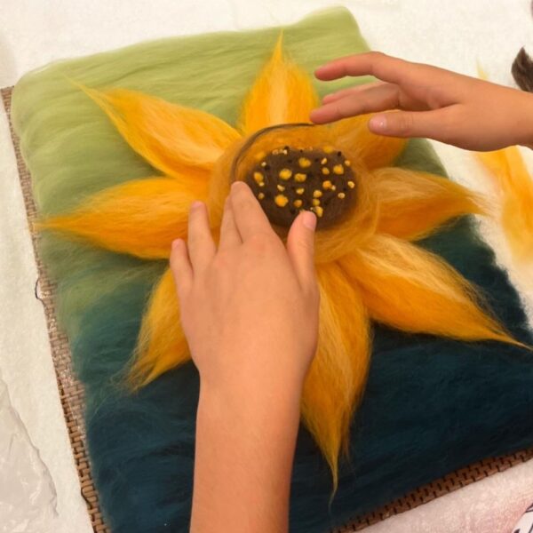 hands creating a yellow sunflower with wool felted