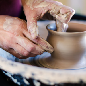 hands throwing pottery on a ceramic wheel