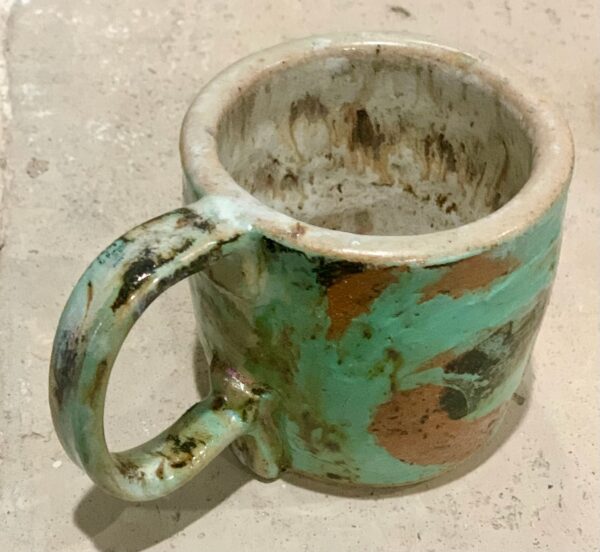 wheel thrown ceramic mug, glazed and resting on a table