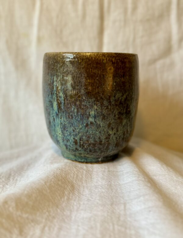 a tall glazed vessel thrown on a pottery wheel