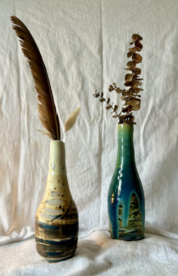 two tall wheel thrown vases glazed and resting on a table