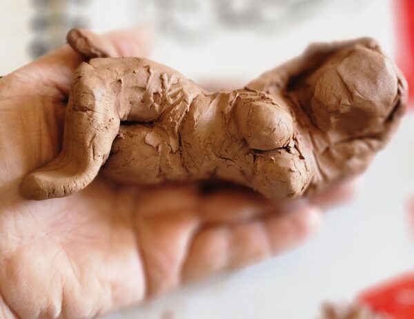 handmade clay figure of a woman in progress, held in hand