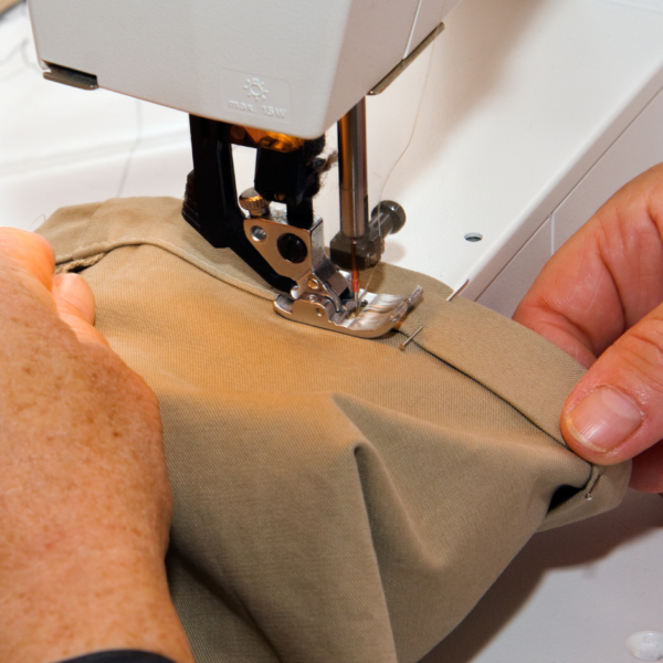 sewing machine with beige pants being hemmed