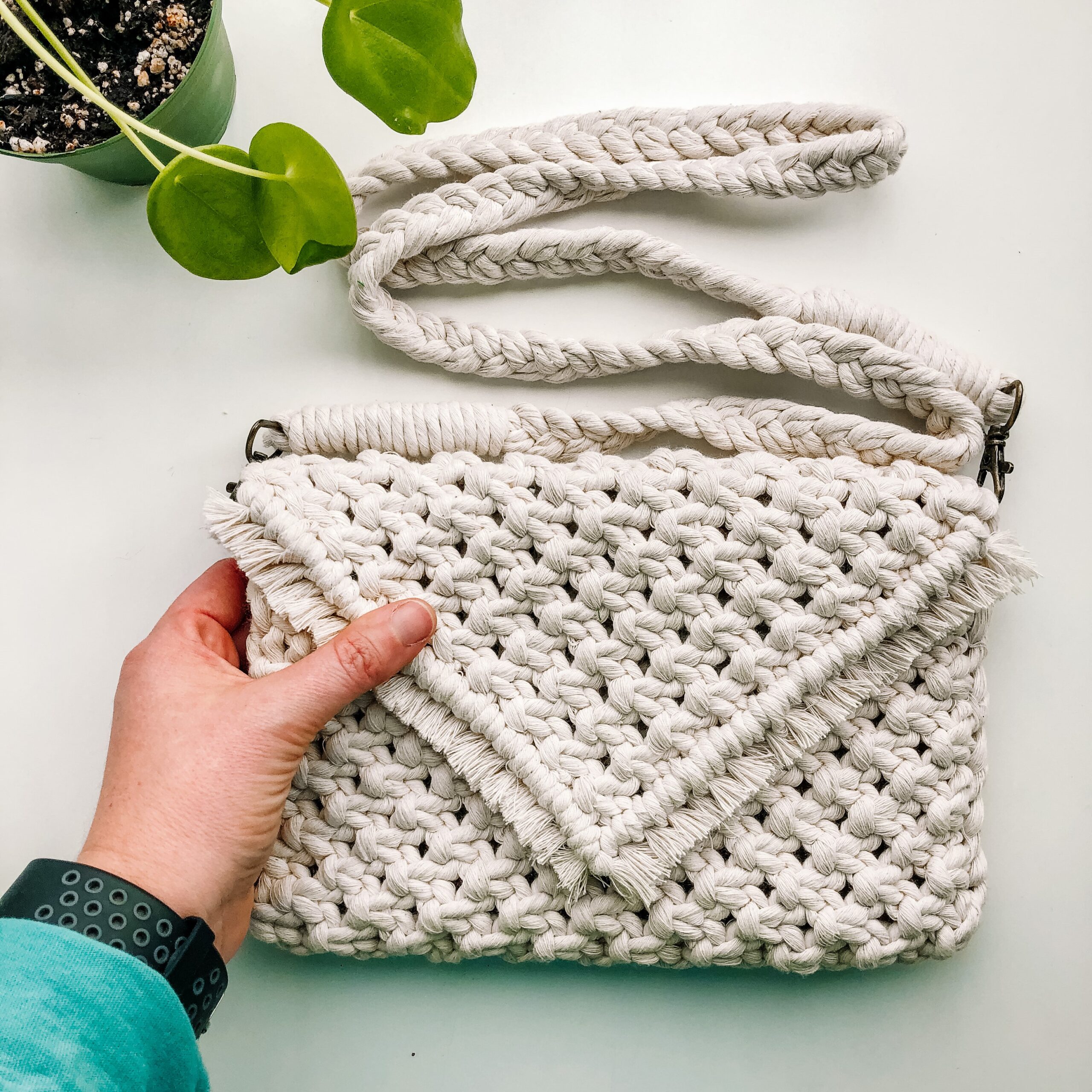 hand holding a macrame' crossbody bag in white rope