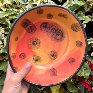 hand holding a piece of clay pottery with tie dye surface design